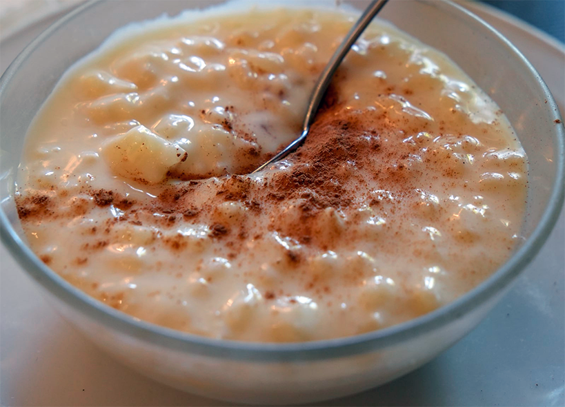 Ivorian rice pudding with cinnamon garnish in a small glass bowl with a spoon