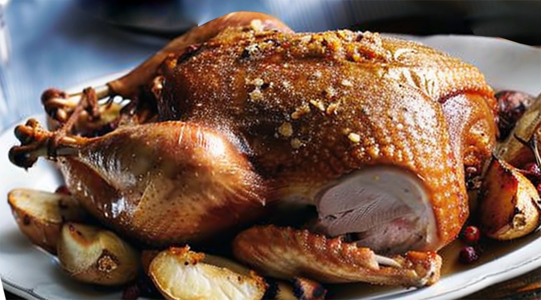 roast goose with potato stuffing served on a bed of roast potatoes