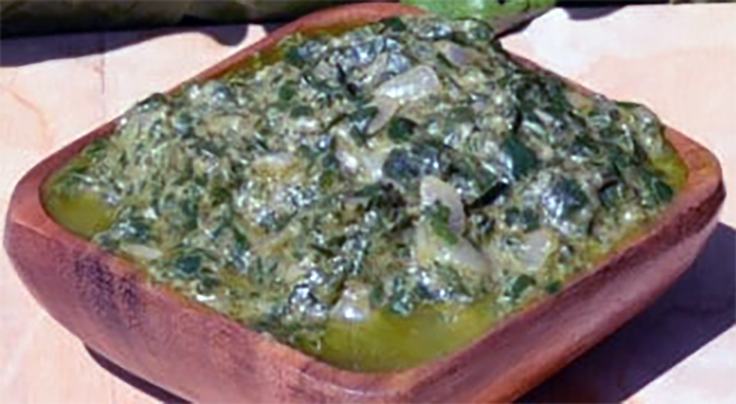 spinach salsa in a peanut base served in a square wooden bowl