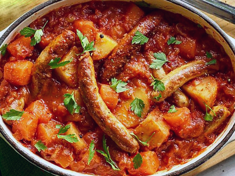 sausage, pumpkin and sage casserole with tomatoes in an oval casserole dish