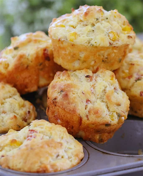savoury cornmeal muffins piled on top of a muffin tin