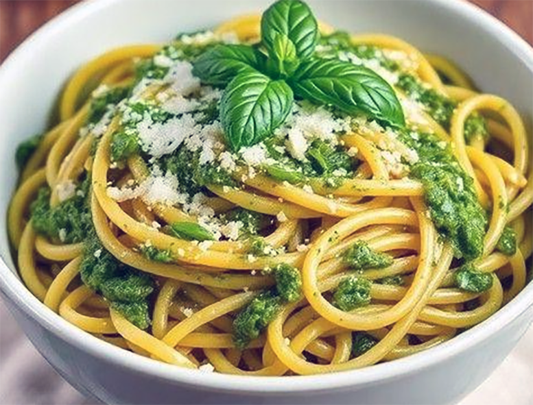 spaghetti with shredded sea aster leaves in a bowl topped with a sprig of basil