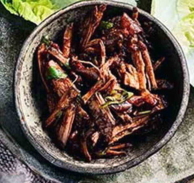 shredded barbacoa beef cooked in a slow cooker shown in a bowl