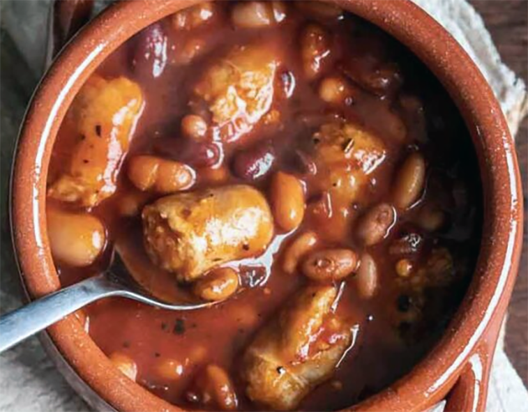 stew of baked beans and sausages in an earthenware bowl
