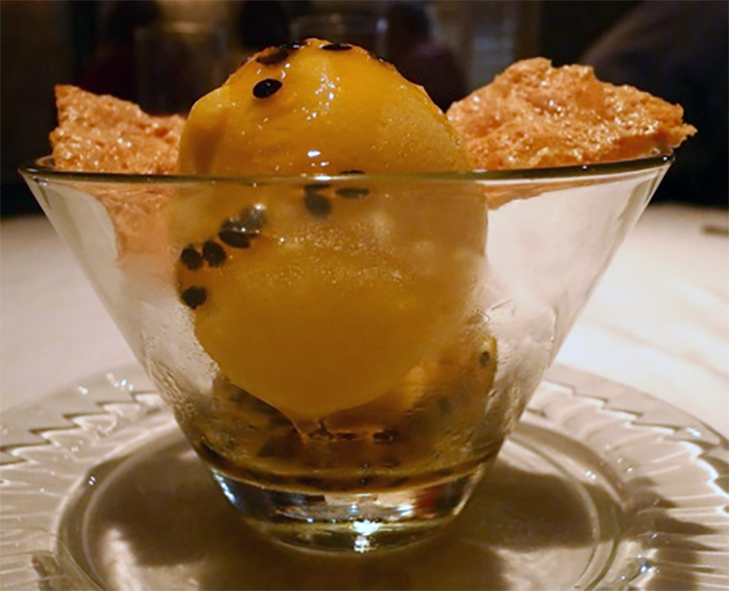 scoop of African medlar sorbet with african medlar crisps in a glass bowl