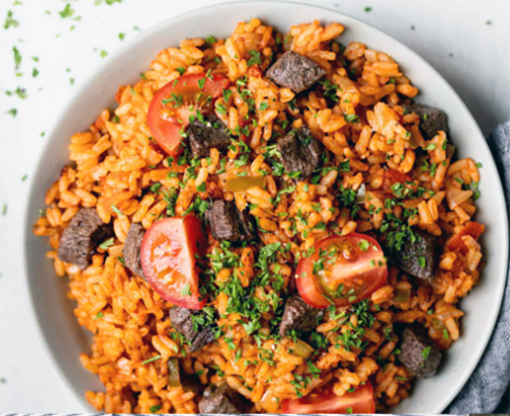 one-pot dish of rice cooked with goat meat in a tomato, onion and chilli base served on a white plate