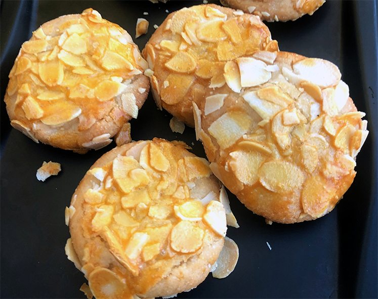 almond drop biscuits topped with slivered almonds on a metal tray