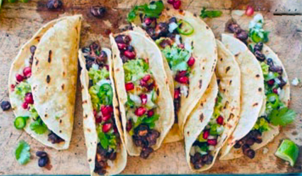 six spicy black bean tacos on a wooden chopping board