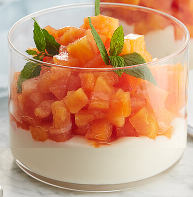 diced spicy papaya garnished with mint sprigs served on a bed of youghurt