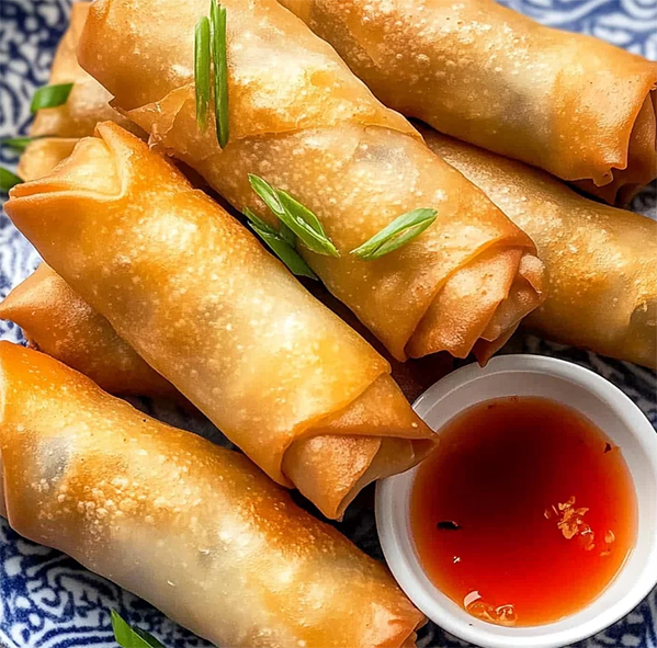 pork and prawn spring rolls on a plate with a dipping sauce