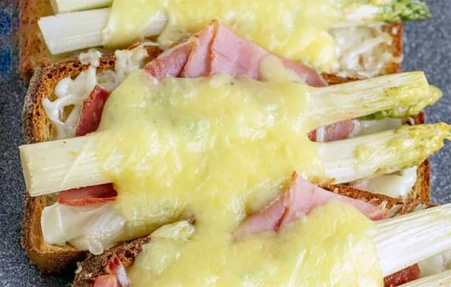 spears of white asparagus served on toast with ham and melted cheese