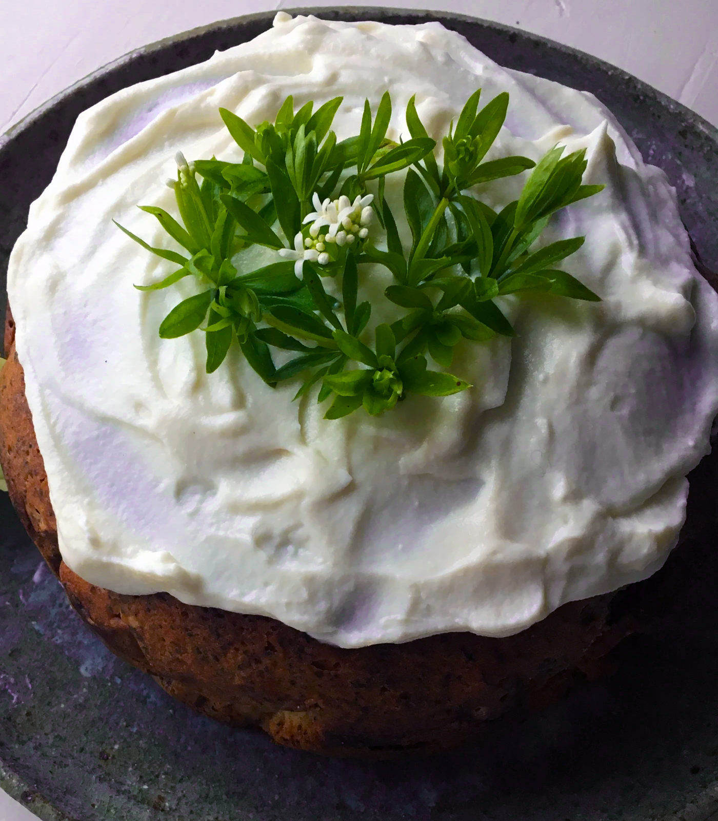 Sweet woodruff and marzipan cake topped with white ricotta icing and a sprig of sweet woodruff</a>