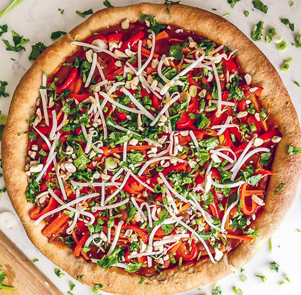 boboli pizza crust topped with peanut sauce, beansprouts, bell peppers, cheese and prawns