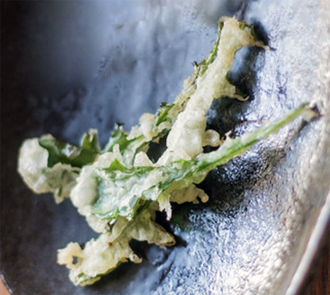 two three-cornered leek flower stems in tempura batter served on a plate
