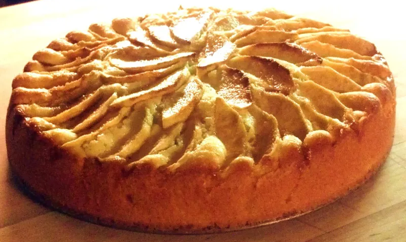 Italian rustic apple cake with an apple wedge topping on a wooden table