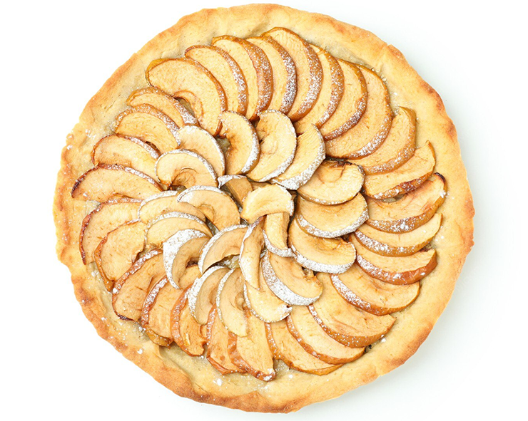 layered tart of sliced apples against a white background