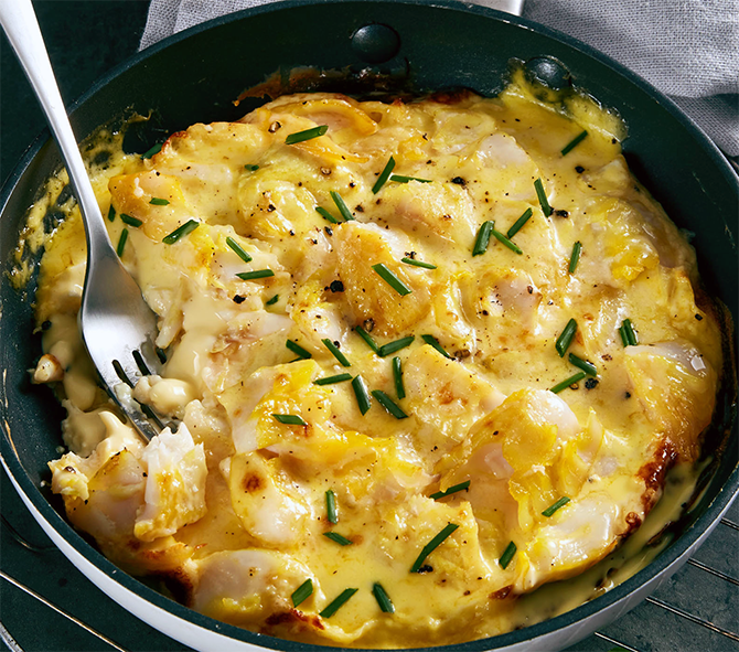 omelette Arnold Bennet garnished with chives in a frying pan with a fork