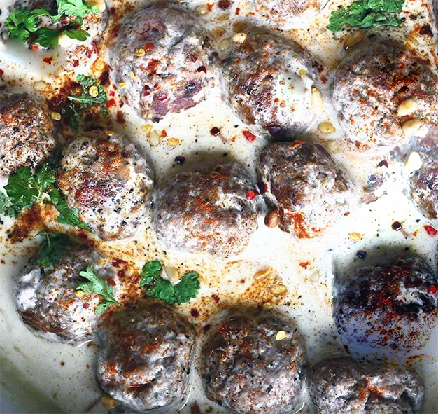 meatballs served in a spiced yoghurt sauce with parsley leaves