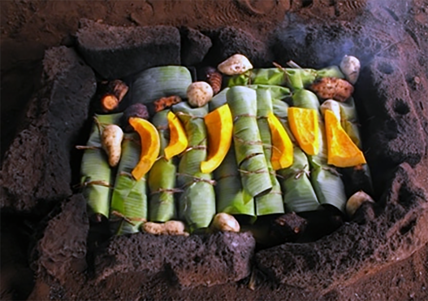 umu or volcanic rock pit oven with food placed inside in banana leaves prior to burying