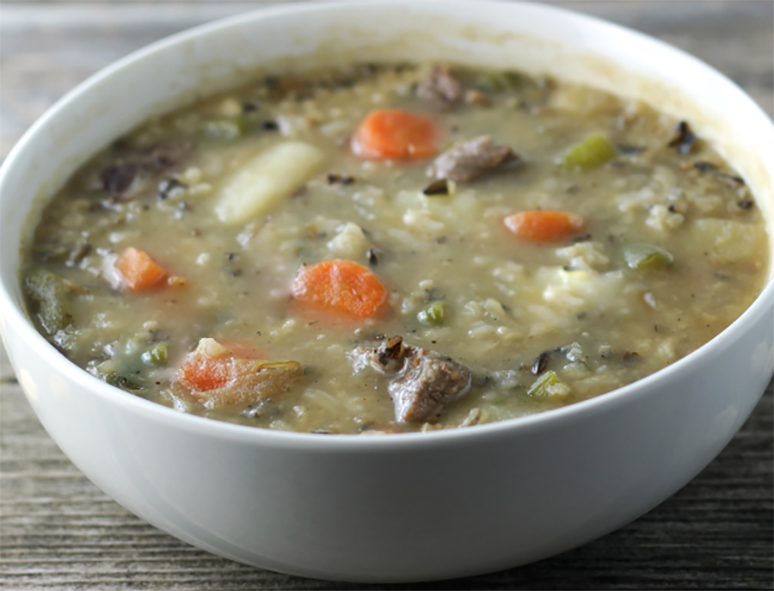 beef, vegetable and rice soup in a beer base served in a white bowl