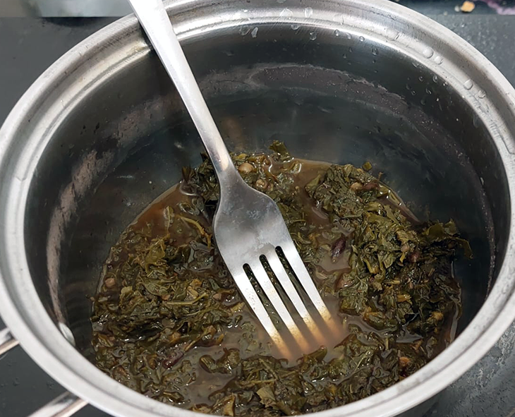 Puree of wild greens in a saucepan with a fork