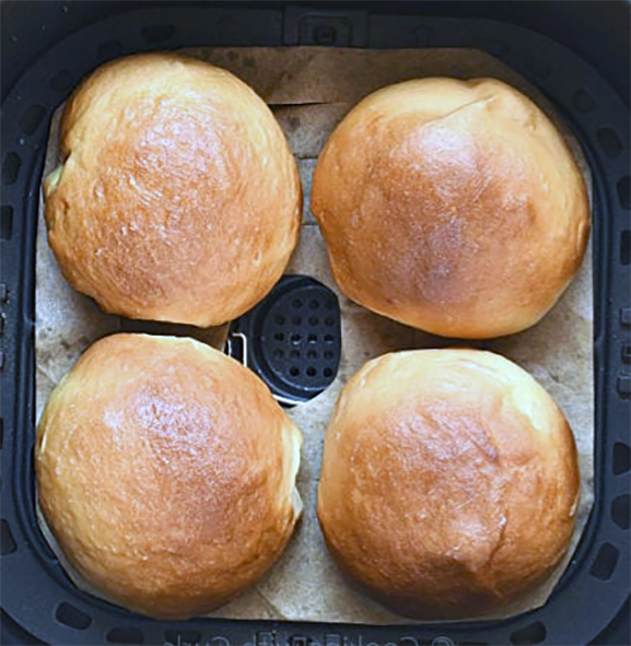four burger buns shown in an air fryer basket