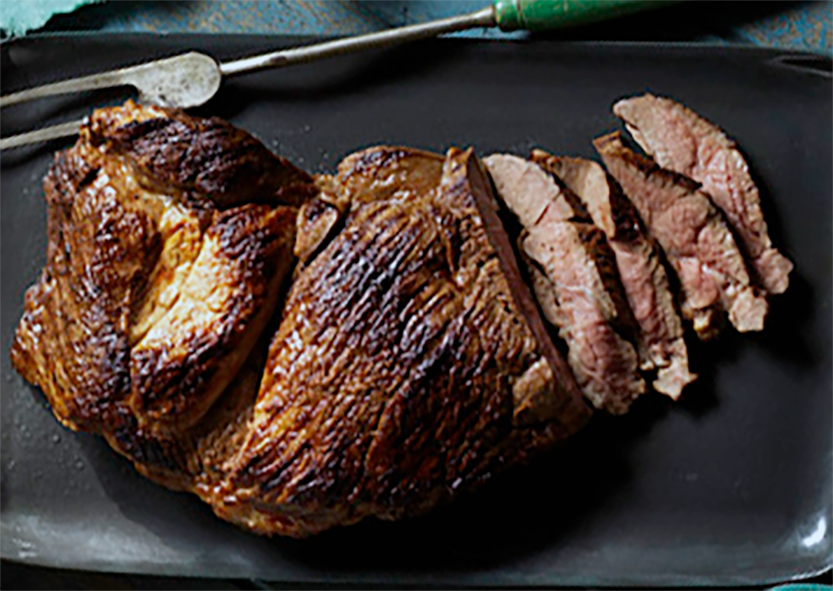 Barbecued Butterflied Lamb Leg on a plate with one end sliced