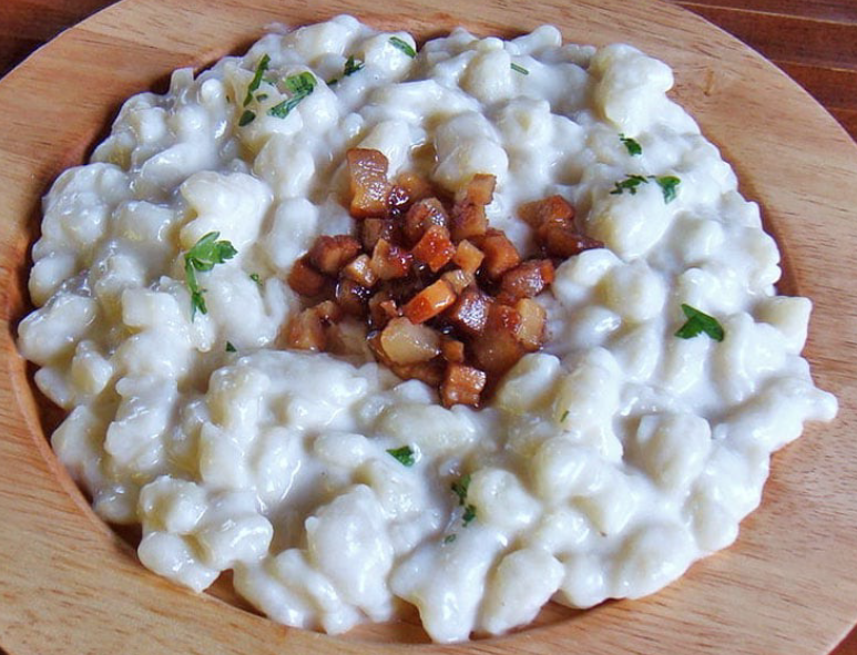 Bryndzové Halušky, Slovakian dumplings blended with creamy cheese and served in a wooden plate with a garnish of bacon