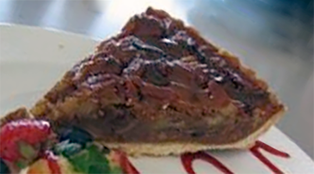 cajun fig and pecan pie served on a plate with strawberries and strawberry coulis