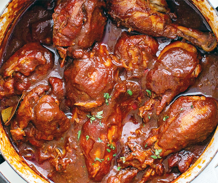 Chicken pieces in chocolatey adobo sauce cooked in a casserole dish