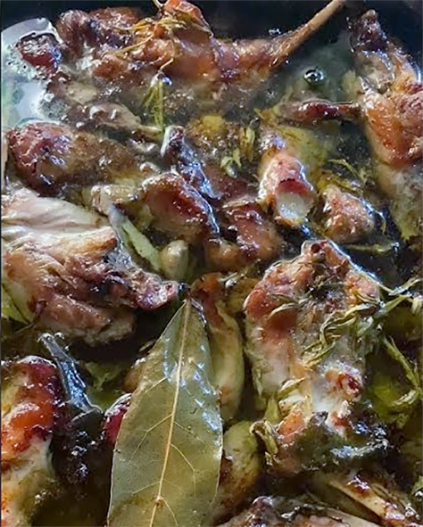 confit of wild rabbit pieces in duck fat with bay leaf in a roasting tin