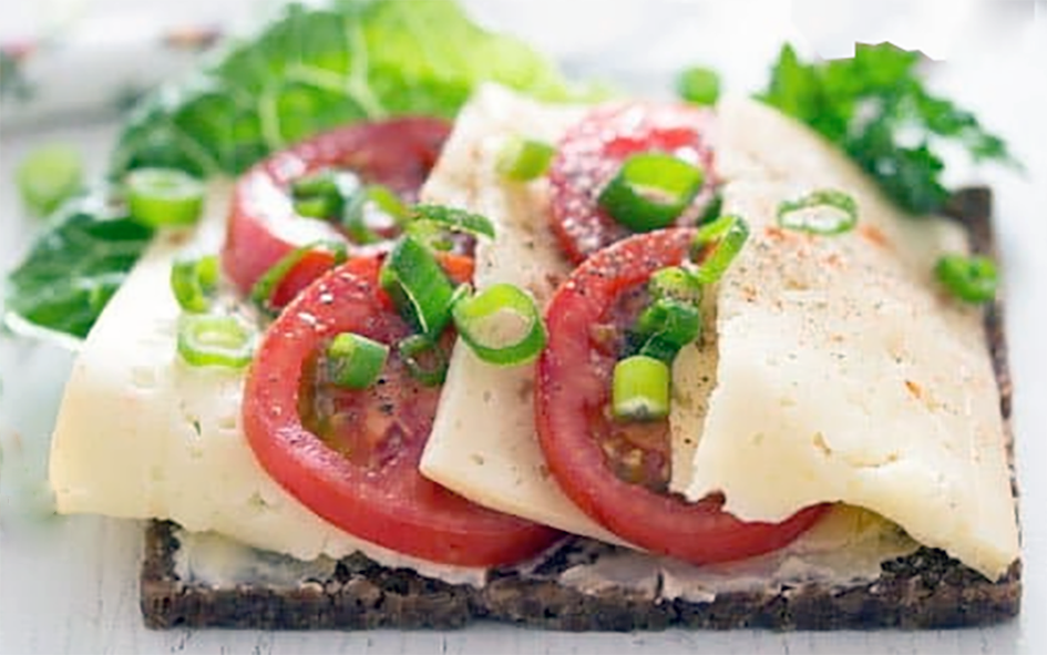 Danish Havarti cheese smorrebrod (open sandwich) with a topping of cheese, tomatoes, lettuce and spring onions