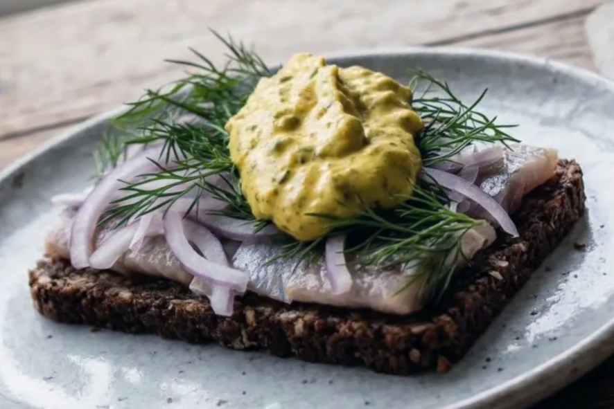 Smørrebrød, Danish open faced sandwich topped with pickled herring, onions, dill and curry remoulade