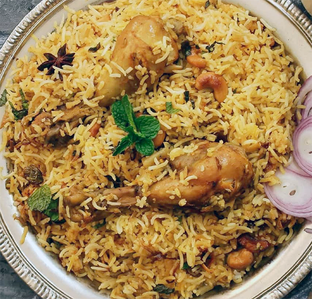 Emirati machboos, one-pot rice and chicken served on a silver platter with a sprig of mint garnish