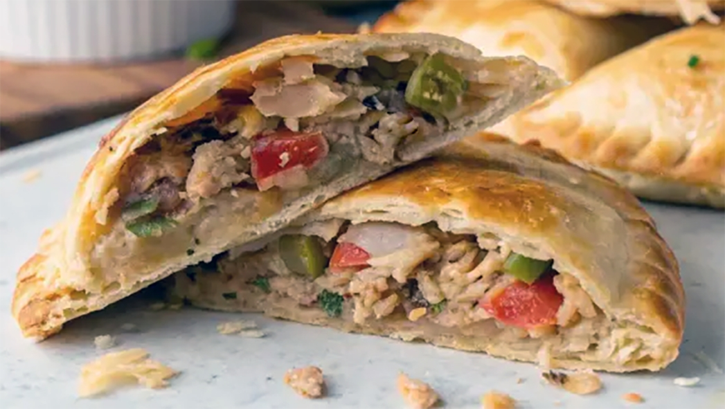 halved Galician empanada revealing the filling on a white counter top