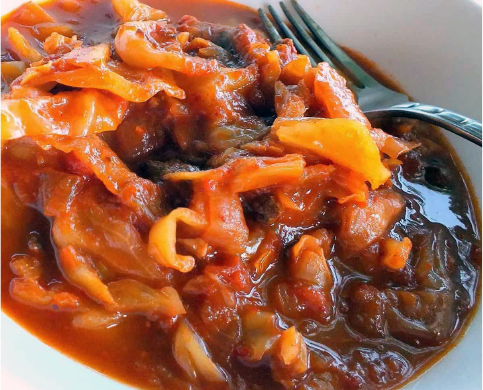 etli kapuska, Turkish cabbage stew with meat served in a white bowl with a fork