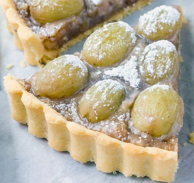 wedge of green grape tart baked in vanilla pastry shown removed from the main tart