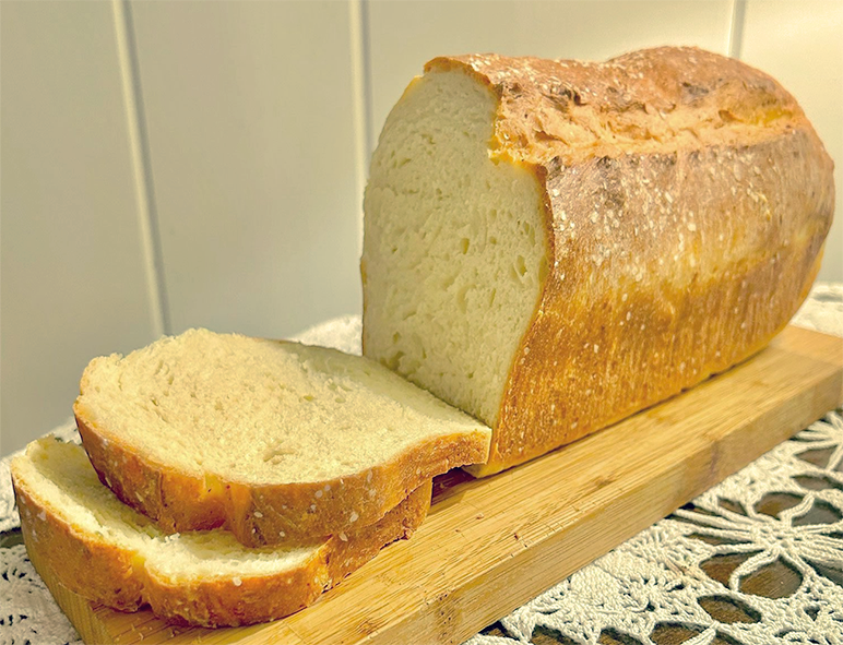 loaf of hazel pollen bread on a wooden cutting board with two slices cut