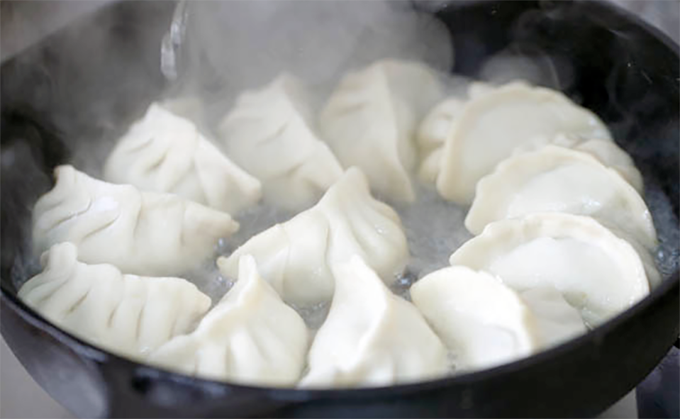 jiazoi dumplings steaming in a wok