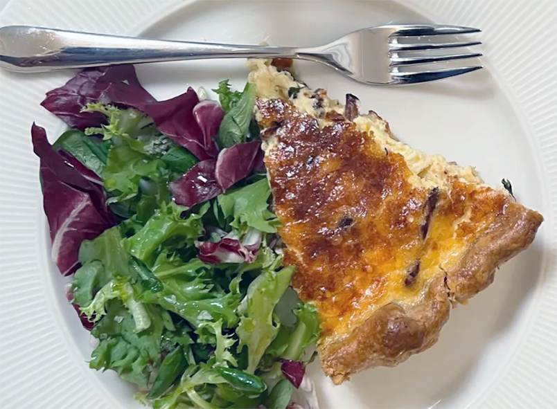 slice of kantarellpaj, Swedish chanterelle quiche with a salad and a fork
