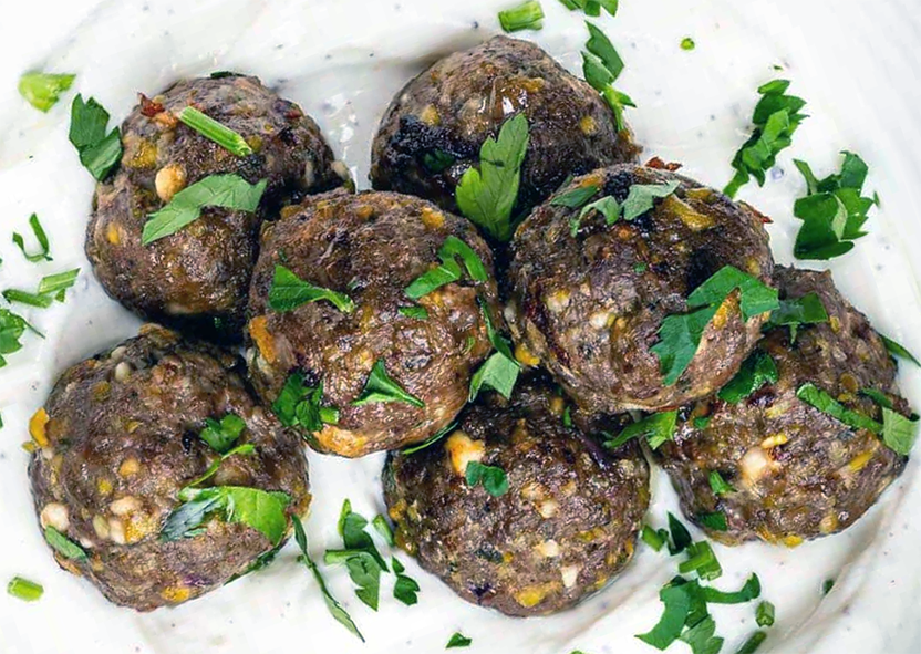 seven keftedes meatballs garnished with chopped parsley arranged on a plate