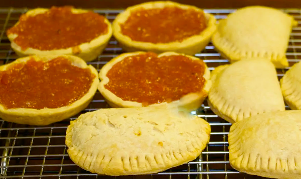 Liberian papaya pies cooked as tartlets and half-moon pasties shown cooling on a wire rack