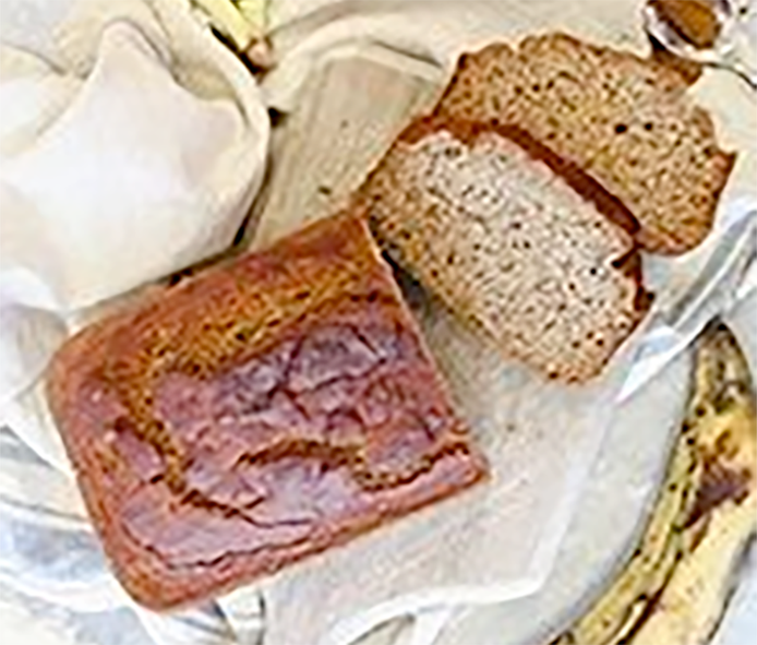 Liberian rice bread made with rice semolina and plantains on a chopping board with two slices cut