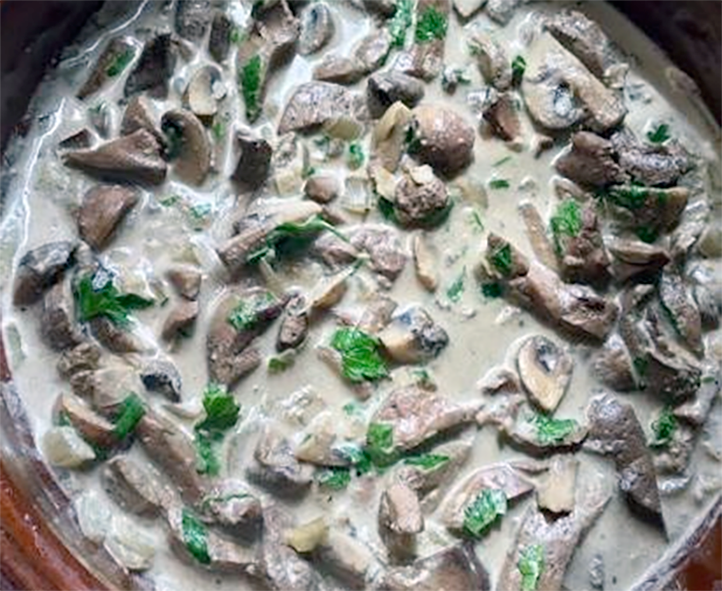 liver with st georges mushrooms in a cream sauce cooked in a ceramic casserole garnished with flat-leaf parsley