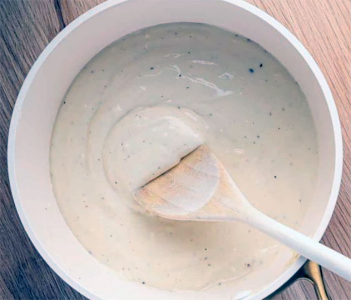 Long-method Béchamel Sauce stirred with a wooden spoon in a saucepan