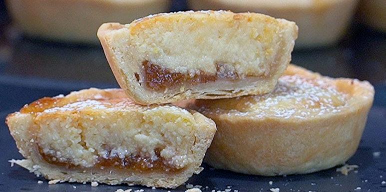 two maids of honour tartlets on a plate with one split to show the jam and filling