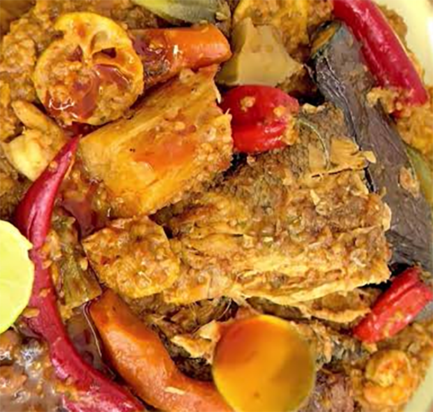 fish and mixed vegetables served on a bed of cooked and spiced rice