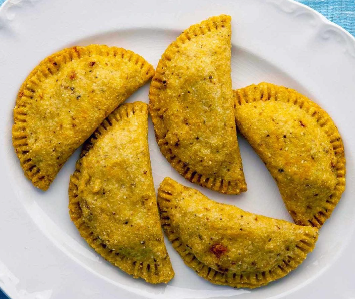 Five Mexican masa empanadas arranged on a white serving plate