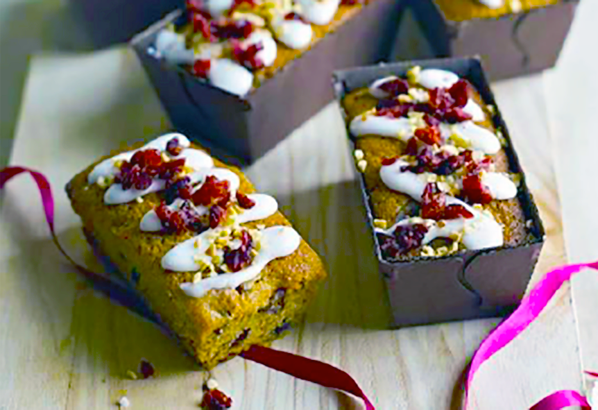 Mini mincemeat and cranberry loaves on a chopping block, one in the baking tin and one extracted
