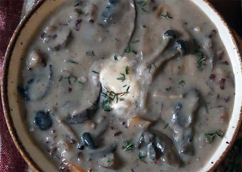 wild mushroom soup in a bowl garnished with soured cream and thyme leaves